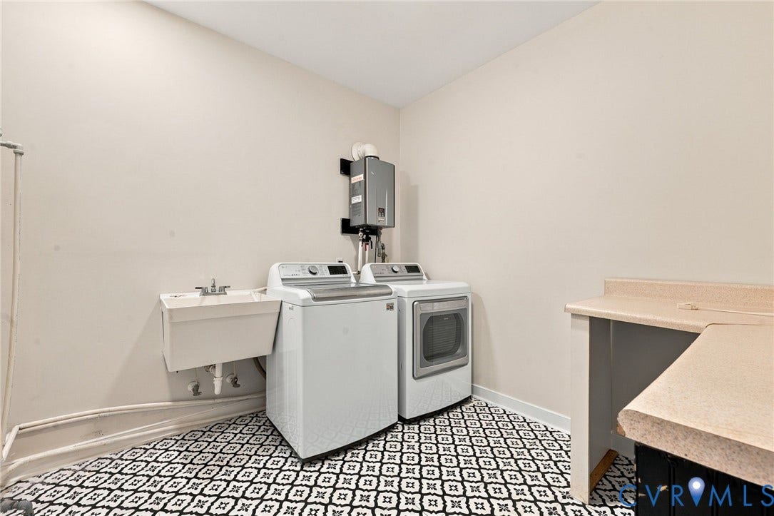 2654 Academy Road, Powhatan, VA 23139 Utility space featuring a wall-mounted tankless water heater, a utility sink, patterned tile flooring, and a built-in countertop