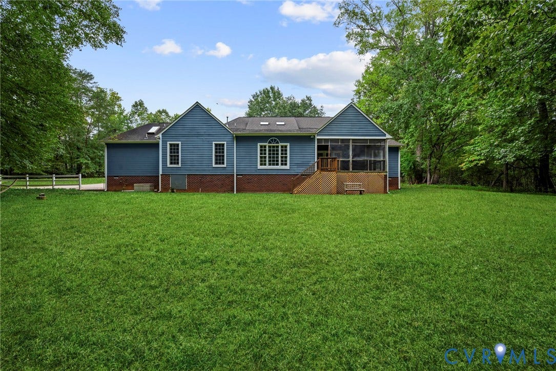 2654 Academy Road, Powhatan, VA 23139 Rear exterior featuring horizontal lap siding, brick foundation, screened-in porch, skylights, and expansive lawn. Virtually edited grass