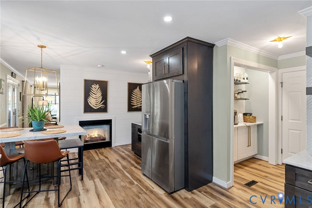 4427 Tweedsmuir Court, Midlothian, VA 23120 Kitchen featuring dark-finish cabinetry, stainless steel refrigerator, white plank wall detailing, inset fireplace, and wood-finish flooring