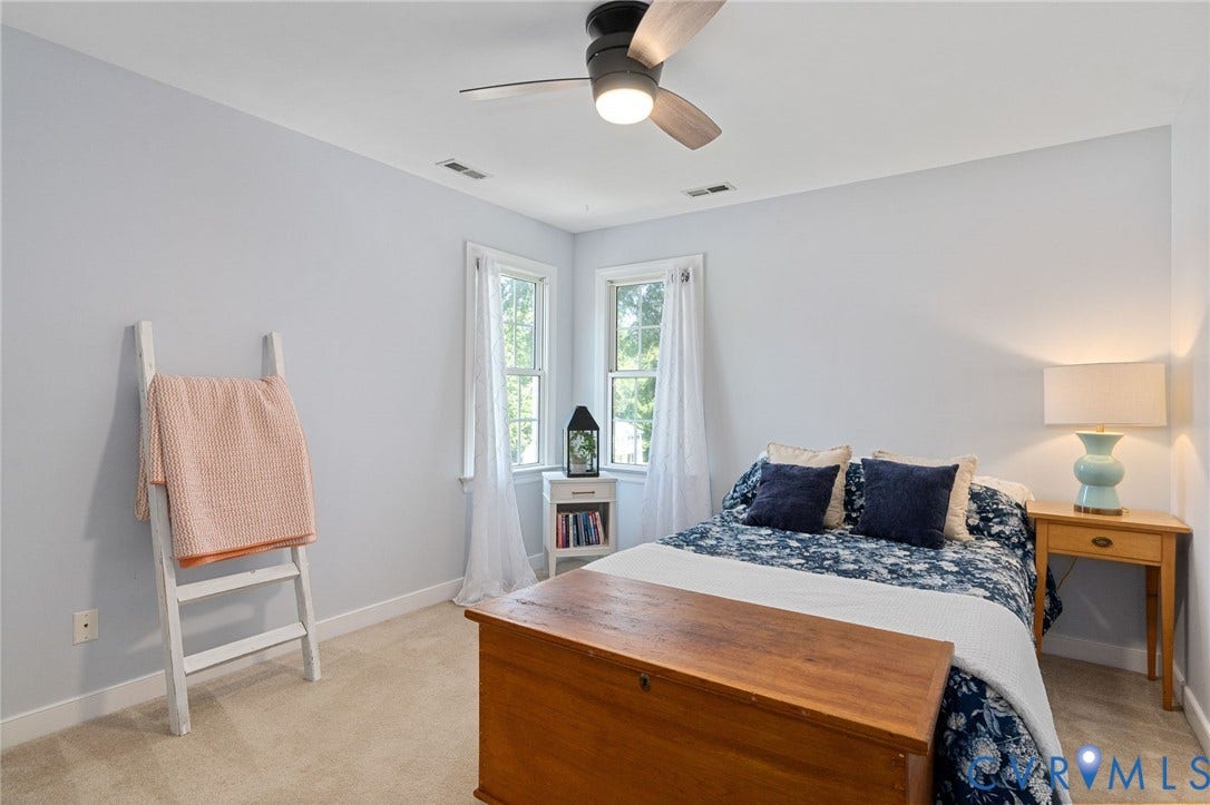 4427 Tweedsmuir Court, Midlothian, VA 23120 Neutral-toned interior space featuring light-colored wall-to-wall carpeting, dual-aspect windows, and a multi-blade ceiling fan with an integrated light fixture