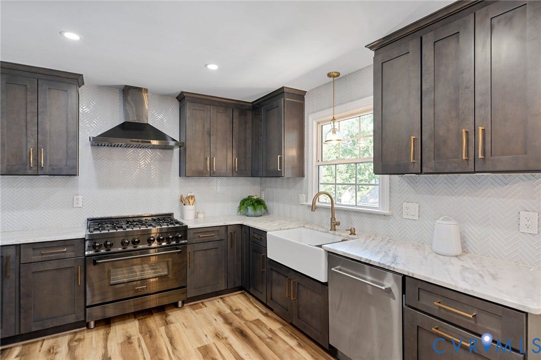 4427 Tweedsmuir Court, Midlothian, VA 23120 Kitchen featuring custom cabinetry with brass hardware, chevron-pattern tile backsplash, farmhouse sink, stone countertops, and a professional-grade stainless steel range with a matching chimney-style hood