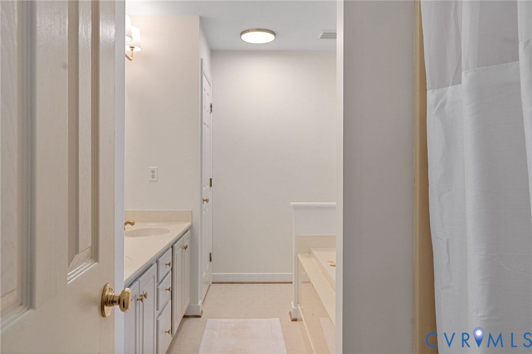 4427 Tweedsmuir Court, Midlothian, VA 23120 Dual-sink vanity with light-toned cabinetry, surface-mounted lighting, and a built-in tub with tile surround