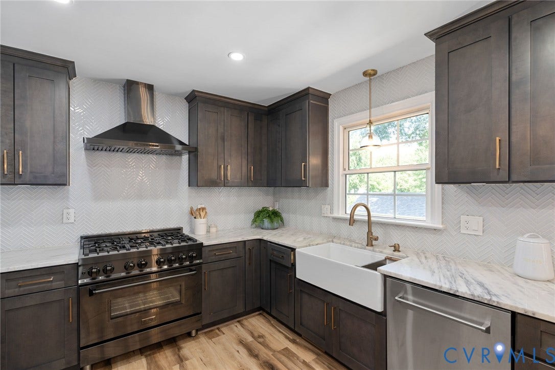 4427 Tweedsmuir Court, Midlothian, VA 23120 Kitchen featuring dark-finish cabinetry with gold-toned hardware, stone-surface countertops, white herringbone-patterned tile backsplash, farmhouse-style sink with a brass-finish faucet, and stainless steel professional-grade gas range with a matching ventilation hood