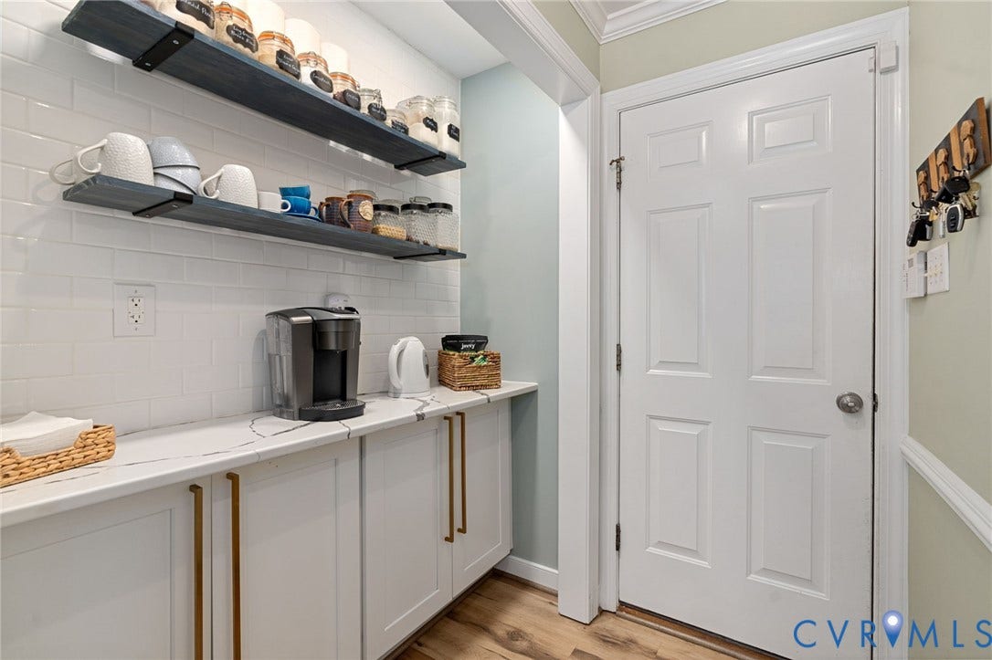 4427 Tweedsmuir Court, Midlothian, VA 23120 Built-in cabinetry with metallic pulls, stone-composite countertop, white subway tile backsplash, dual wall-mounted wood-finish shelving, and wood-finish flooring