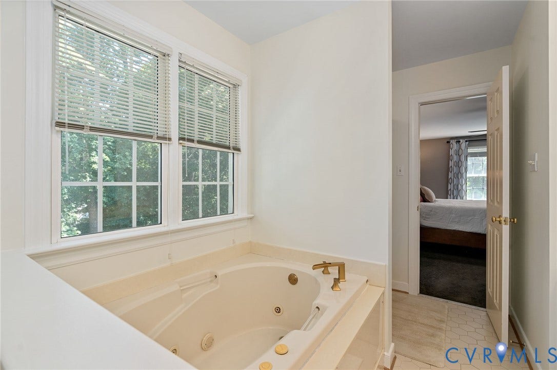 4427 Tweedsmuir Court, Midlothian, VA 23120 Jetted soaking tub with brass-finish hardware, surrounding stone-finish tile deck, and multi-pane windows