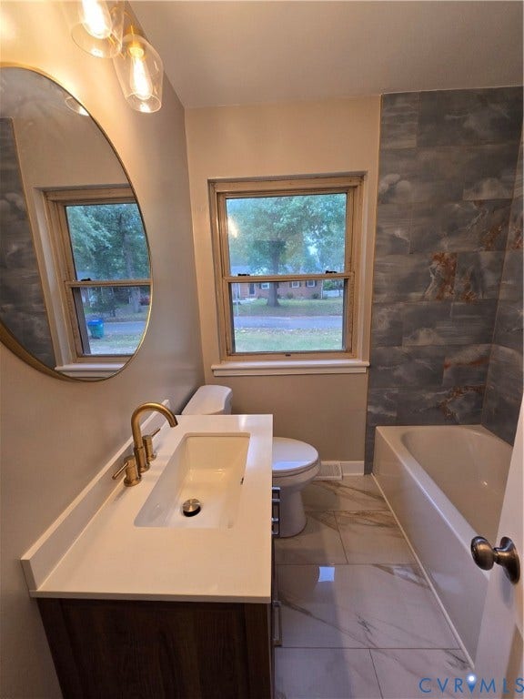 1108 Pierpont Road, Richmond, VA 23225 Bathroom featuring a vanity with a white rectangular sink and brass faucet, round wall-mounted mirror, large-format floor tiling, and a tiled tub surround