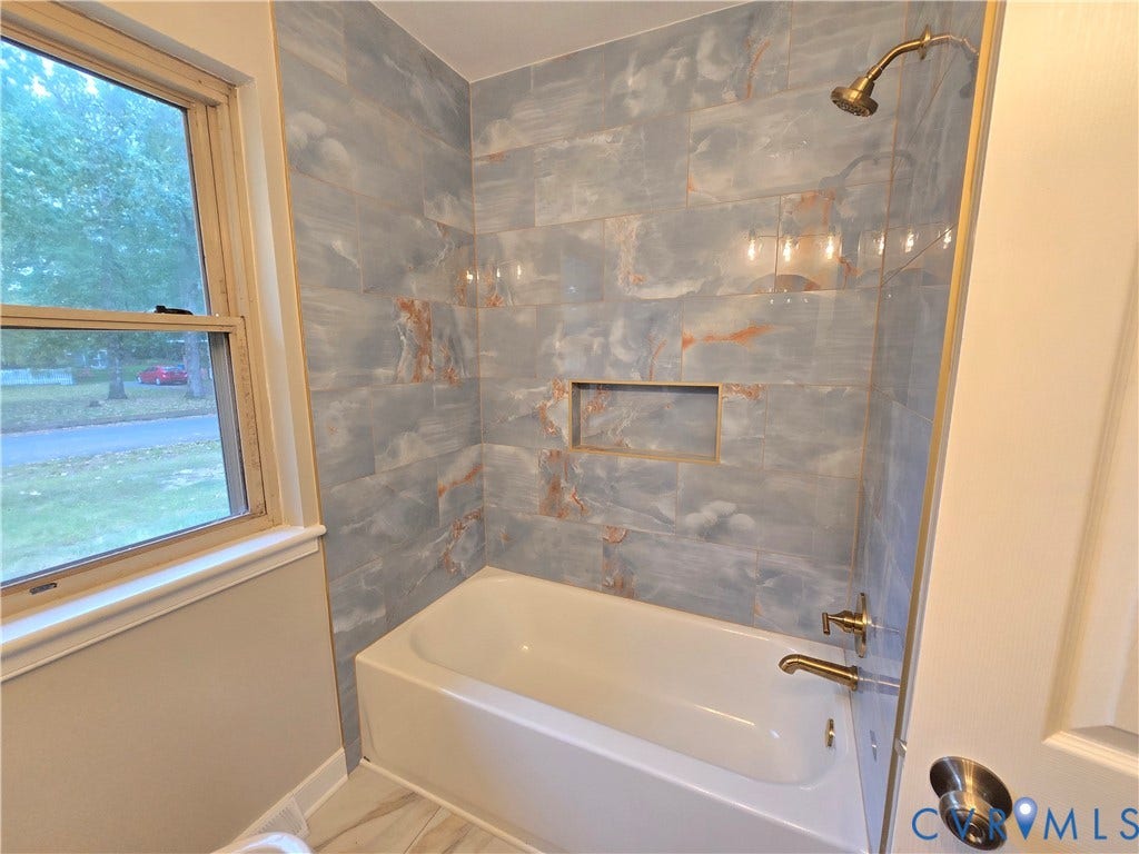1108 Pierpont Road, Richmond, VA 23225 Bathtub surround featuring large-format tile with blue and copper veining, integrated wall niche, and metallic shower hardware