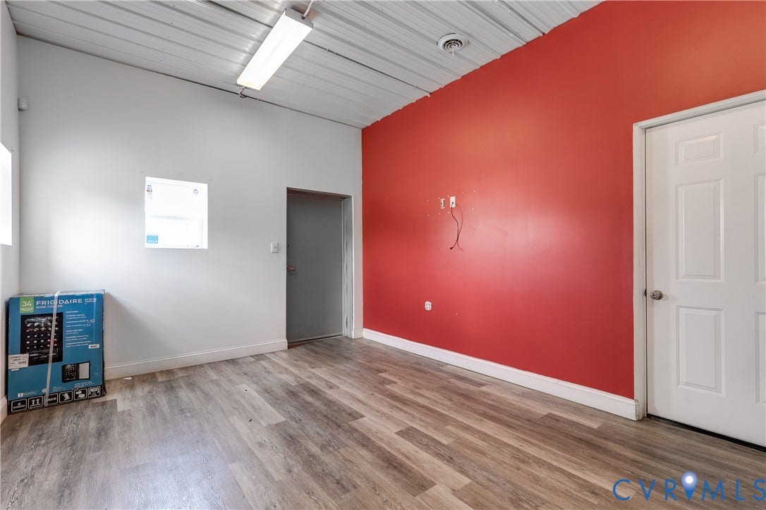 3300 Hull Street, Richmond, VA 23224 Interior room featuring wood-finish flooring, a ribbed metal ceiling, and linear fluorescent lighting