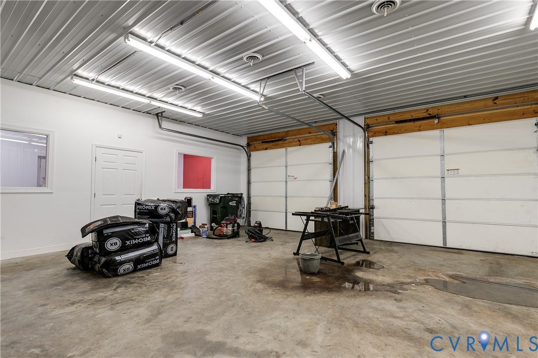 3300 Hull Street, Richmond, VA 23224 Multi-car garage featuring dual overhead doors, concrete flooring, high-clearance metal panel ceiling, and integrated fluorescent lighting
