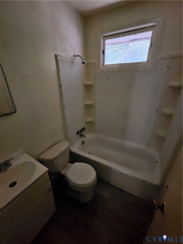 Bathroom featuring a tub-shower combination with integrated shelving, a wall-mounted showerhead, a porcelain vanity sink, and a high-set window