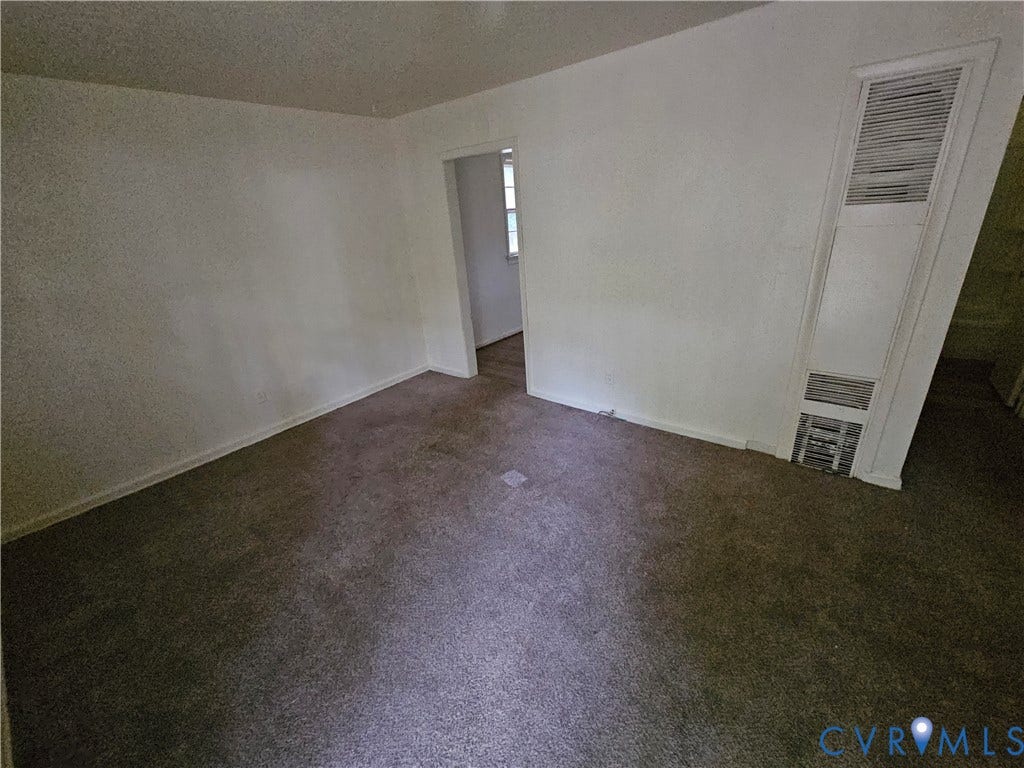 Neutral-toned carpeting, wall-mounted heating unit, and interior doorway