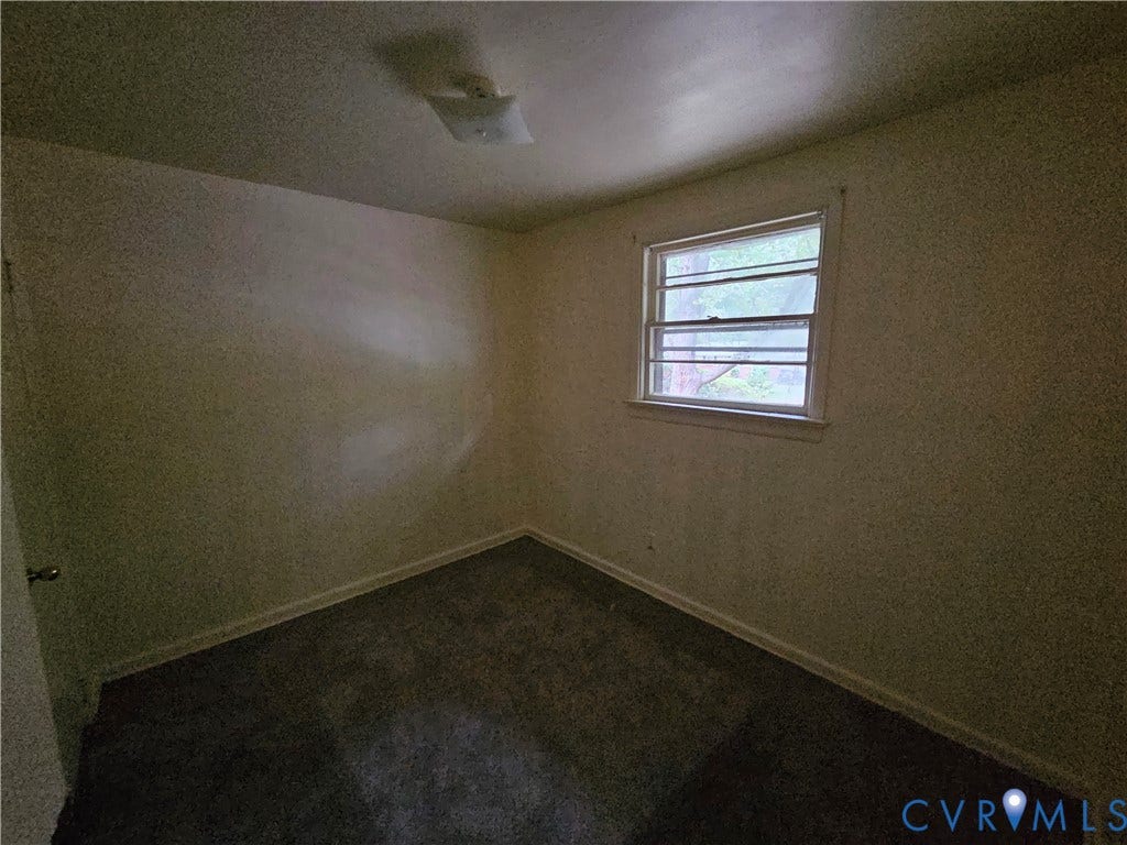 Neutral-toned walls, carpeted flooring, window with a horizontal grid pattern, and a flush-mount ceiling light fixture