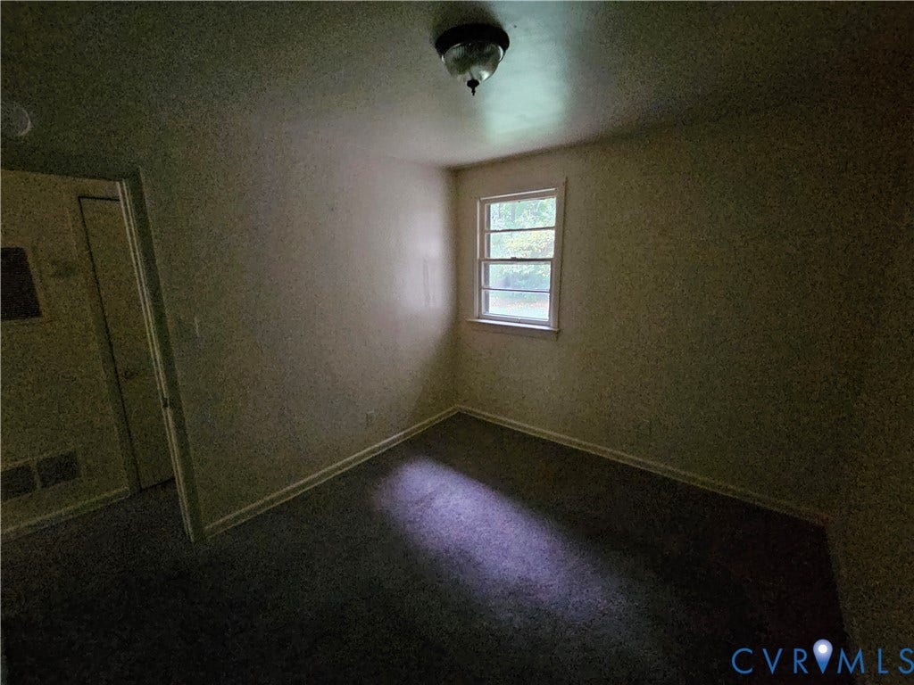 Interior space featuring neutral wall tones, carpeted flooring, a multi-pane window, and a ceiling-mounted light fixture