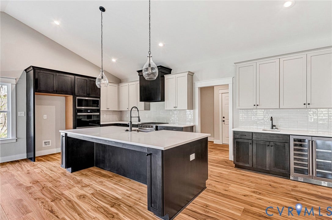 8860 Emily Jane Place, Quinton, VA 23141 Open concept kitchen featuring hardwood floors, a spacious central island with a sink, white countertops, and both light and dark cabinetry
