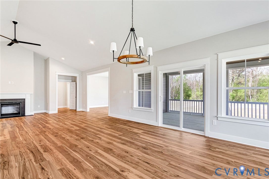 8860 Emily Jane Place, Quinton, VA 23141 Spacious living area featuring hardwood floors, a fireplace with a white mantle, an exposed beam chandelier, and access to an outdoor deck