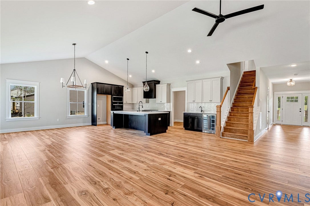 8860 Emily Jane Place, Quinton, VA 23141 Expansive open-concept living area featuring light wood flooring, a kitchen with an island, and a prominent staircase