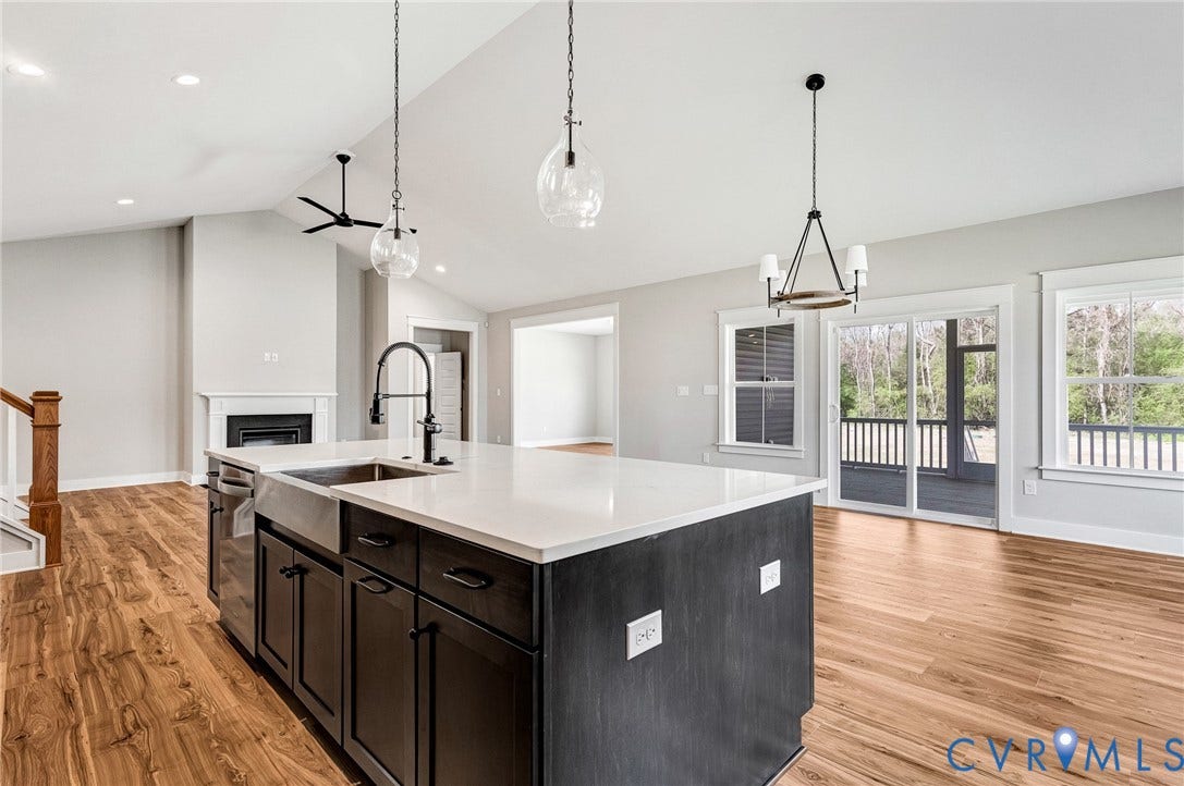 8860 Emily Jane Place, Quinton, VA 23141 The property features an open-concept living area with vaulted ceilings, hardwood style flooring, a contemporary kitchen island with a farmhouse sink, and a fireplace