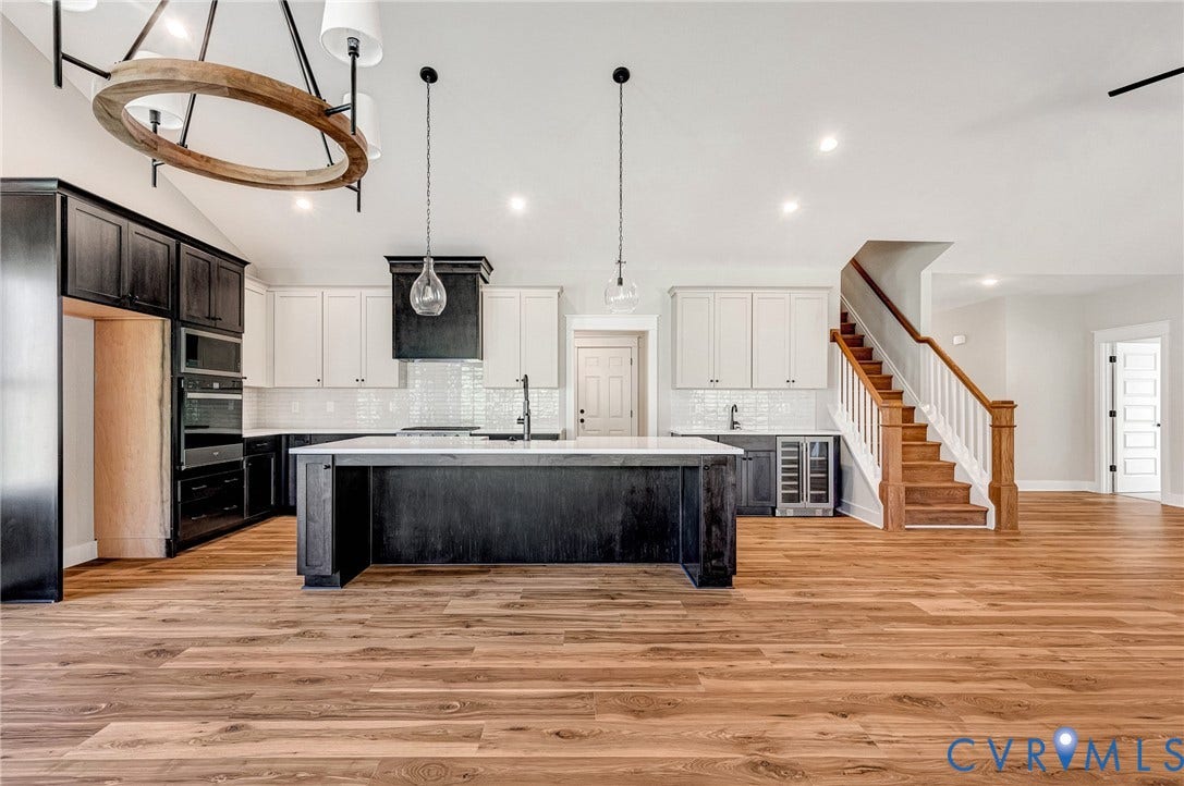 8860 Emily Jane Place, Quinton, VA 23141 Expansive open-concept living area featuring wood flooring, a kitchen with an island, and a staircase with natural wood treads and railing