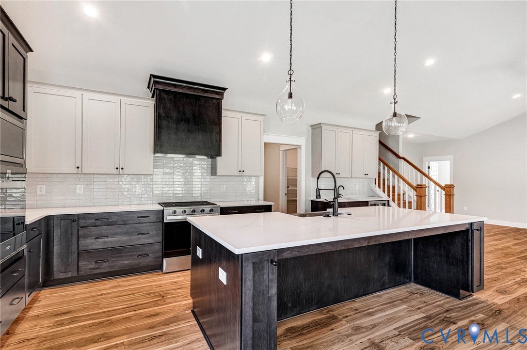 8860 Emily Jane Place, Quinton, VA 23141 The kitchen features a large island with a white countertop, two-tone cabinetry, a stainless steel range, and a white subway tile backsplash