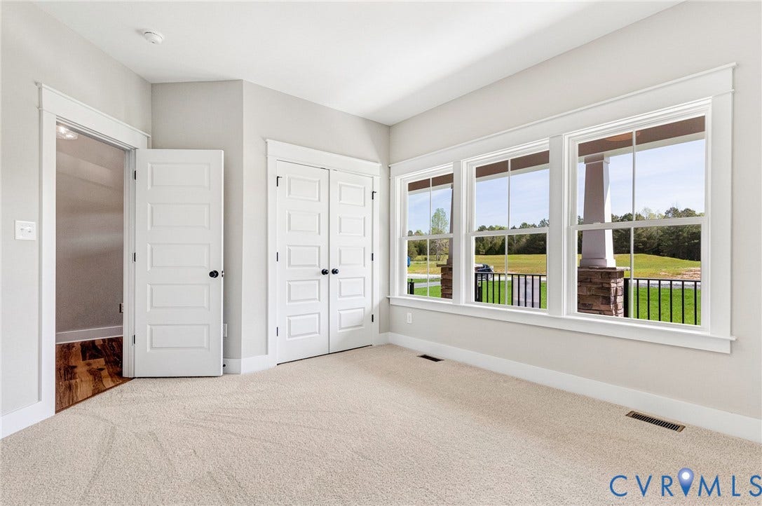 8860 Emily Jane Place, Quinton, VA 23141 This inviting room features light-colored carpeting, three large windows offering views of green landscaping, and white paneled doors with black hardware