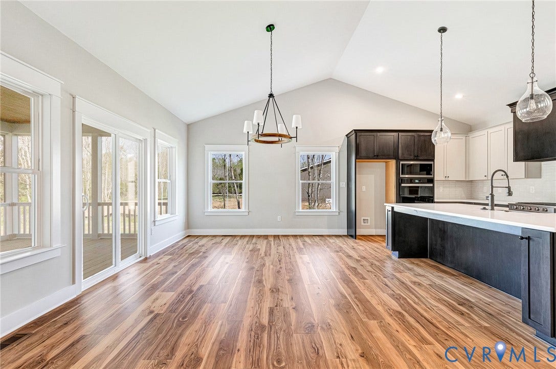 8860 Emily Jane Place, Quinton, VA 23141 Spacious open concept living area featuring vaulted ceilings, rich hardwood flooring, a modern kitchen with a large island and pendant lighting, and access to an outdoor screened porch