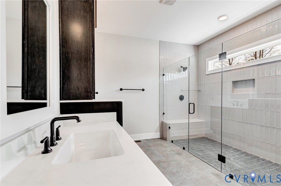 8860 Emily Jane Place, Quinton, VA 23141 The bathroom features a sleek vanity with a rectangular sink and matte black fixtures, a spacious walk-in shower with glass doors, a built-in shower bench, and a horizontal window