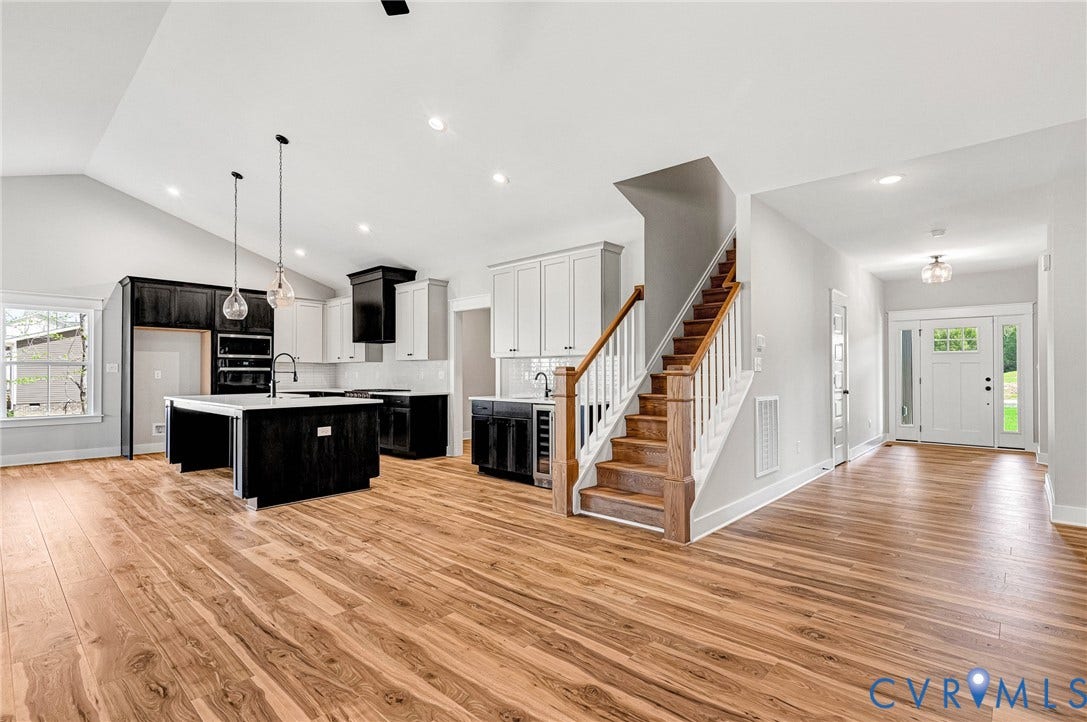 8860 Emily Jane Place, Quinton, VA 23141 Inviting open-concept interior featuring hardwood flooring, a modern kitchen with a central island, and a prominent staircase