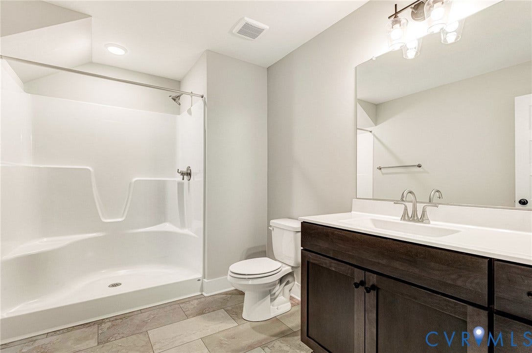 8860 Emily Jane Place, Quinton, VA 23141 Bathroom featuring a white shower stall, a toilet, a vanity with a dark wood finish, a white countertop with an integrated sink, and a large mirror