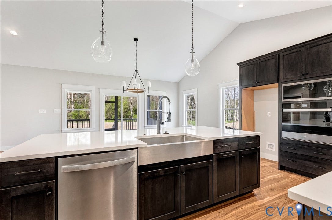 8860 Emily Jane Place, Quinton, VA 23141 The kitchen features a large island with white countertops and a stainless steel farmhouse sink, dark wood cabinetry, and stainless steel appliances