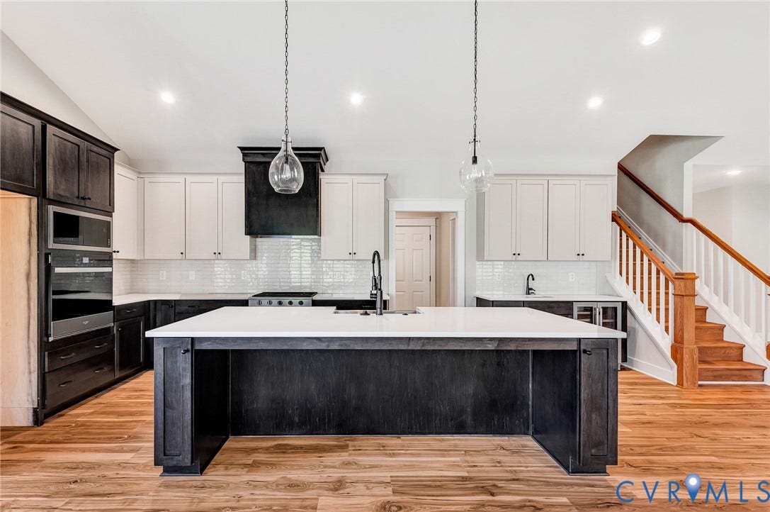 8860 Emily Jane Place, Quinton, VA 23141 The kitchen features a large island with a white countertop and dark cabinetry, pendant lighting, and stainless steel appliances