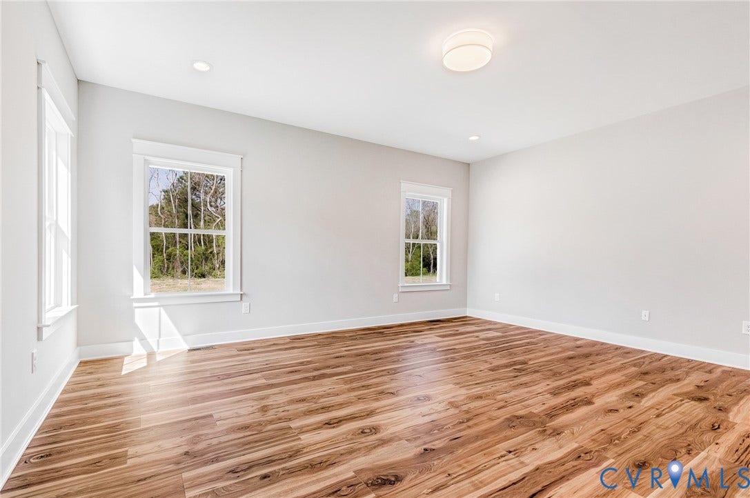 8860 Emily Jane Place, Quinton, VA 23141 This spacious room features light-toned walls, rich wooden flooring, and multiple windows that provide views of outside greenery