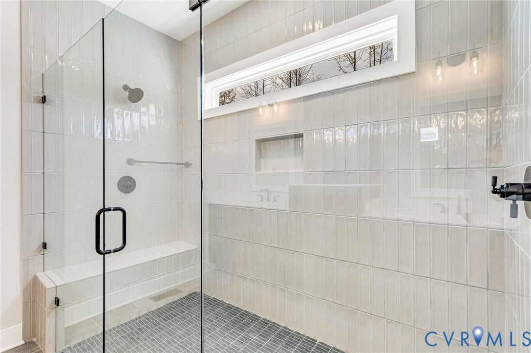 8860 Emily Jane Place, Quinton, VA 23141 The shower features clear glass enclosure, light-colored rectangular wall tiles, and a built-in bench