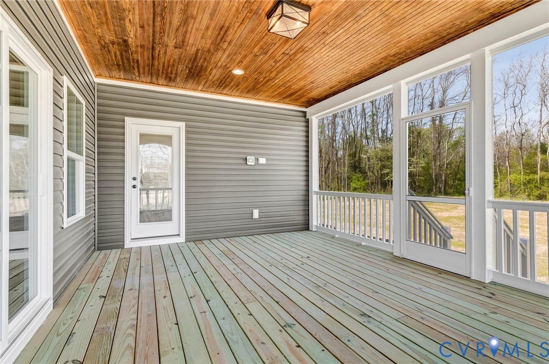 8860 Emily Jane Place, Quinton, VA 23141 The property features a screened-in porch with a wood plank ceiling and a light fixture, offering an outdoor living space with views of mature trees