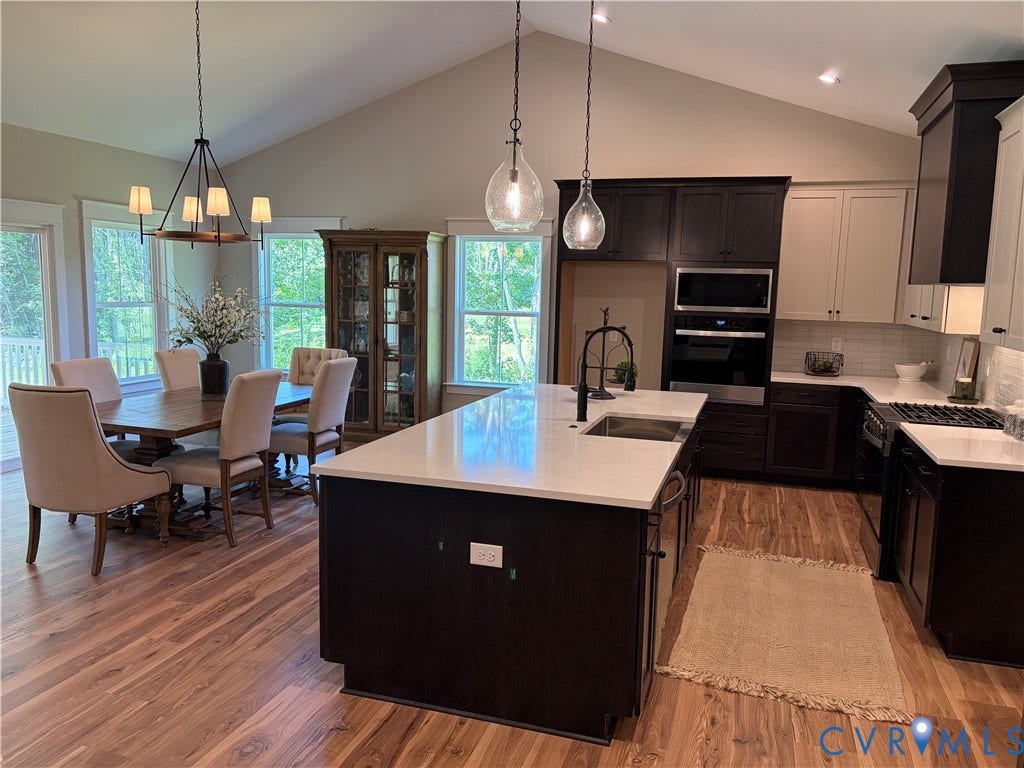 8860 Emily Jane Place, Quinton, VA 23141 Open-concept kitchen and dining area featuring vaulted ceilings, wood-finish flooring, two-tone cabinetry, stainless steel appliances, and a central island with a sink