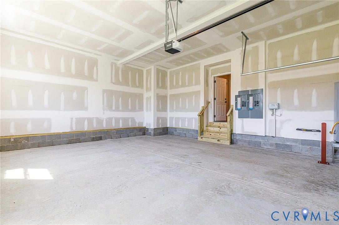 8860 Emily Jane Place, Quinton, VA 23141 Spacious garage featuring a concrete floor, exposed block foundation, and an interior access door with wooden steps