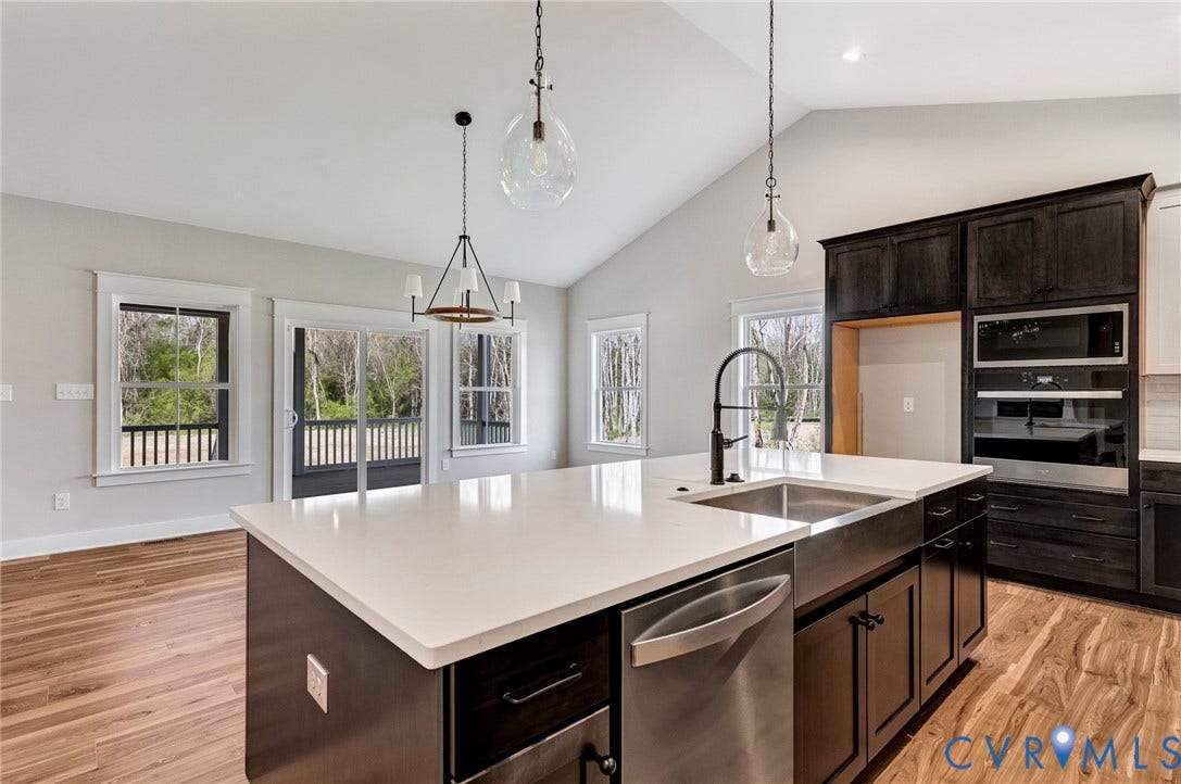 8860 Emily Jane Place, Quinton, VA 23141 Kitchen featuring an island with a stainless steel sink and faucet, integrated dishwasher, and light-colored countertop