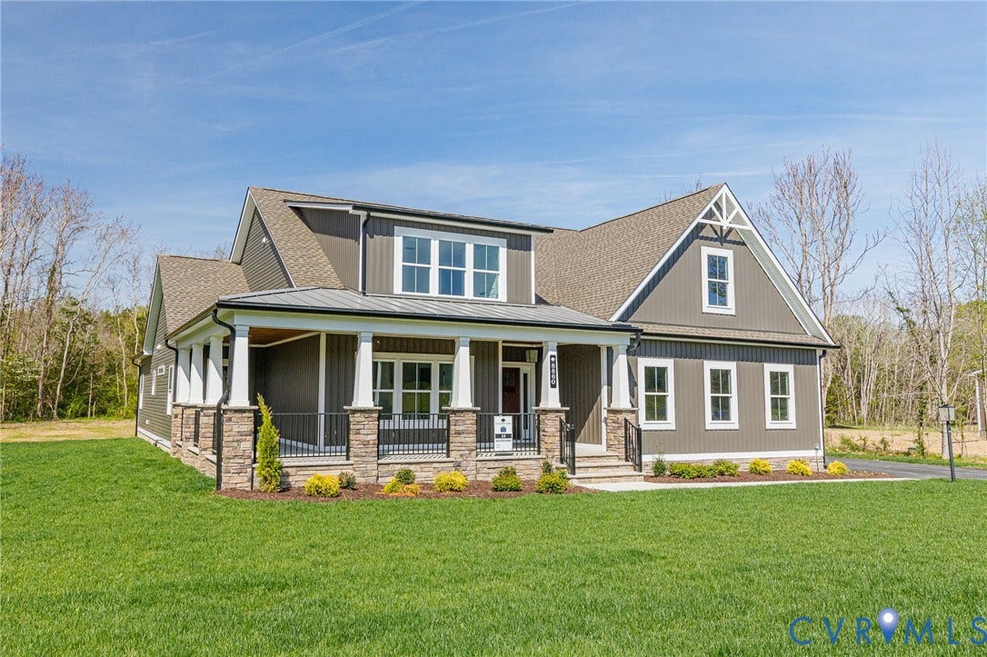 8860 Emily Jane Place, Quinton, VA 23141 The property features a large front lawn, a covered porch with white columns and stone accents, and dark gray siding with white trim