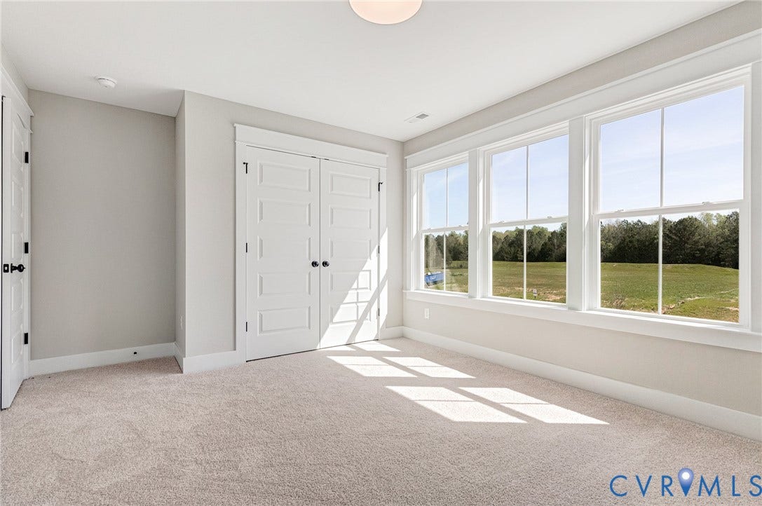 8860 Emily Jane Place, Quinton, VA 23141 The interior space features light-colored walls and carpet, a ceiling light fixture, and white trim around the windows and doors