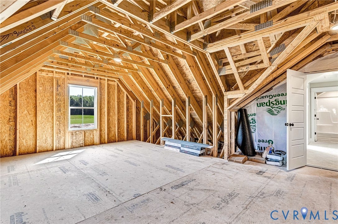 8860 Emily Jane Place, Quinton, VA 23141 Unfinished attic space with exposed wooden beams, a window overlooking a green landscape, and a door leading to a finished interior