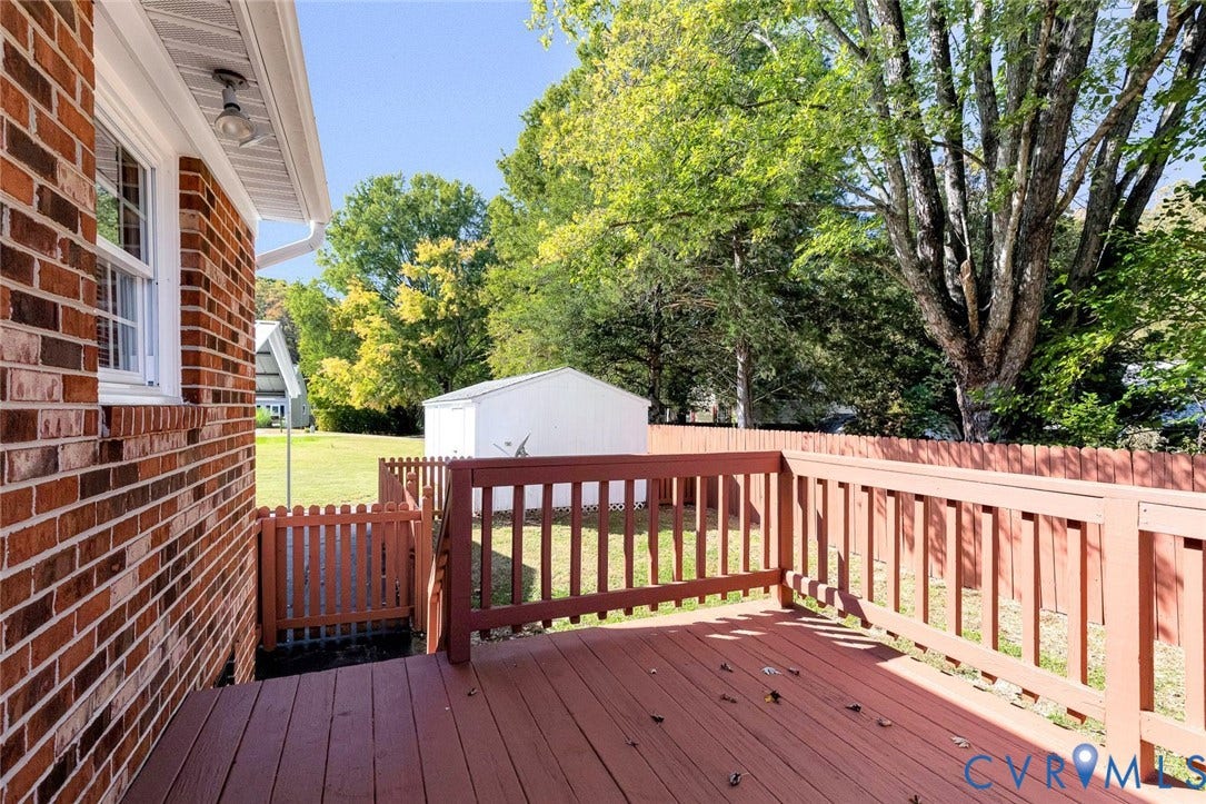 6432 Bellflower Circle, Mechicsville, Mechanicsville, VA 23111 Red brick exterior with a wooden deck, slatted wood perimeter fencing, and a detached metal storage structure