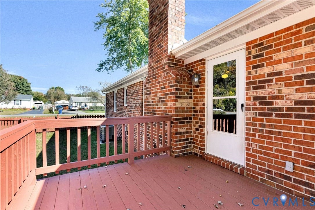6432 Bellflower Circle, Mechicsville, Mechanicsville, VA 23111 Exterior brick facade featuring a raised wooden deck with railings, an integrated brick chimney, and a glass-paneled entry door