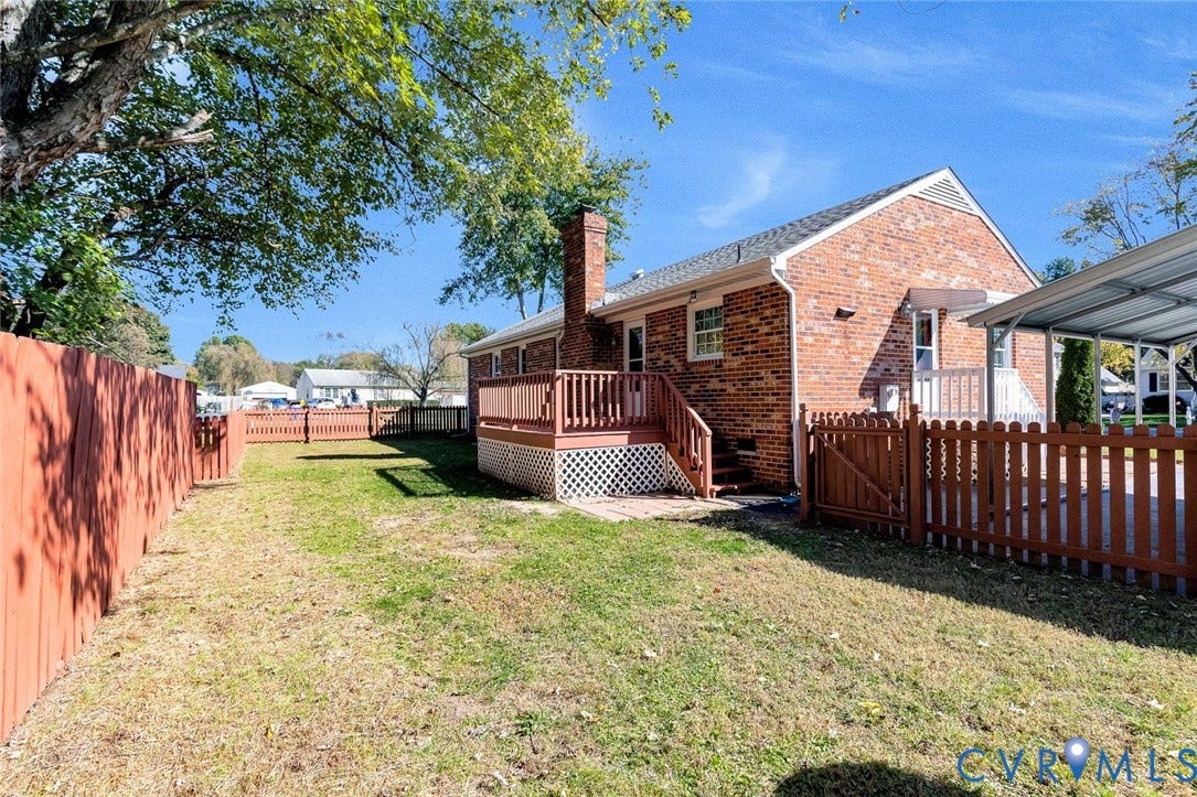 6432 Bellflower Circle, Mechicsville, Mechanicsville, VA 23111 Brick exterior residence featuring a raised wood deck, lattice skirting, metal-covered carport, and enclosed yard with wood privacy fencing