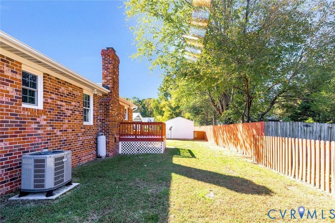 6432 Bellflower Circle, Mechicsville, Mechanicsville, VA 23111 Brick exterior featuring a raised wooden deck, lattice skirting, a detached storage structure, and fenced perimeter