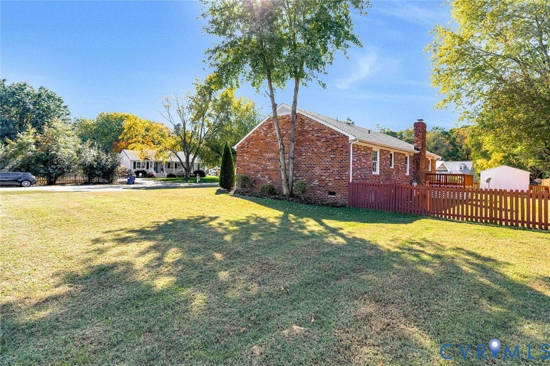 6432 Bellflower Circle, Mechicsville, Mechanicsville, VA 23111 Brick exterior residence featuring an attached chimney, wood-style fencing, and a dedicated outdoor deck area situated on a large lot