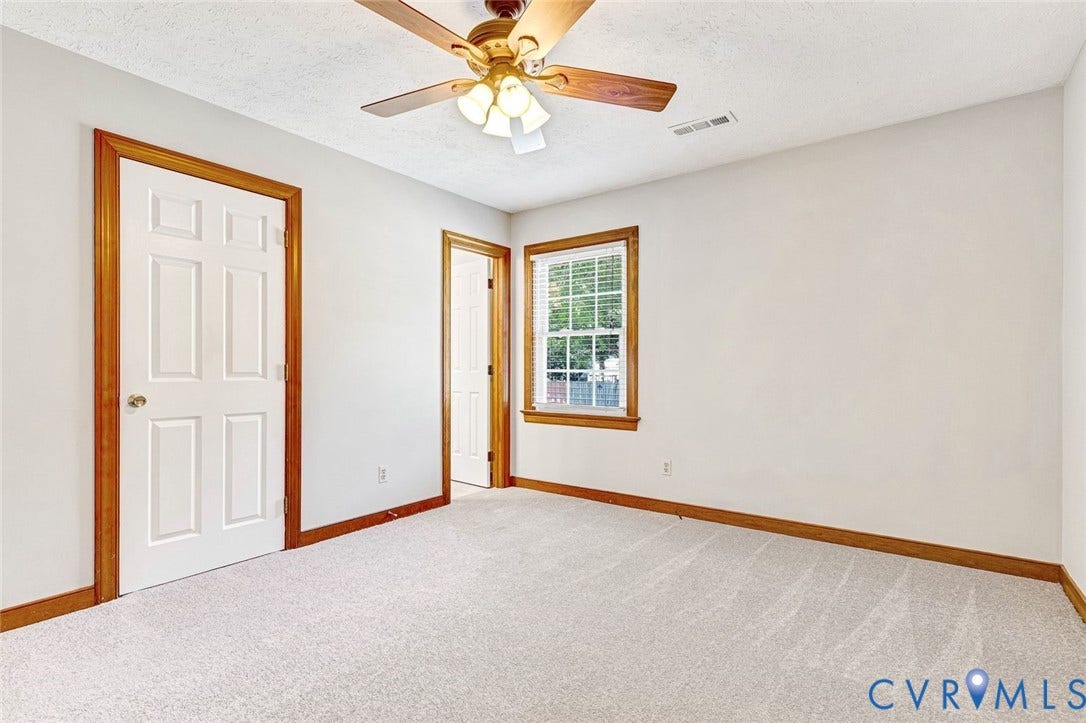6432 Bellflower Circle, Mechicsville, Mechanicsville, VA 23111 Neutral-toned interior space featuring wall-to-wall carpeting, wood-trim door frames, a multi-pane window with wooden casing, and a ceiling-mounted fan with integrated lighting