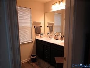 2210 Palm Court, Sandston, VA 23150 Bathroom featuring dark-finished cabinetry, solid-surface countertop with integrated sinks, full-width vanity mirror, and multi-bulb over-mirror lighting