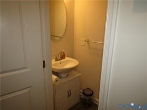 2210 Palm Court, Sandston, VA 23150 White cabinet vanity with a pedestal-style sink, oval wall-mounted mirror, and metallic hardware finish