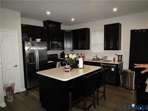 2210 Palm Court, Sandston, VA 23150 Kitchen featuring dark cabinetry, quartz countertops, a center island with integrated seating, stainless steel appliances, and wood-finish flooring