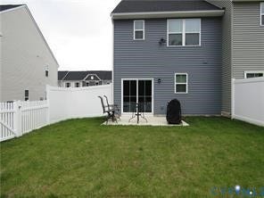 2210 Palm Court, Sandston, VA 23150 Rear exterior featuring horizontal vinyl siding, a concrete patio, and a white privacy fence enclosing the grass lawn