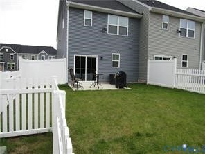 2210 Palm Court, Sandston, VA 23150 Rear exterior featuring lap siding, concrete patio, and white vinyl privacy fencing enclosing a grass lawn